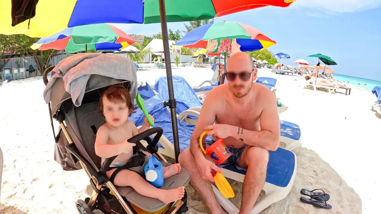 Un papà e il suo bambino si godono una giornata di sole alle Maldive con bambini, tra giochi sulla sabbia e relax sotto gli ombrelloni colorati.