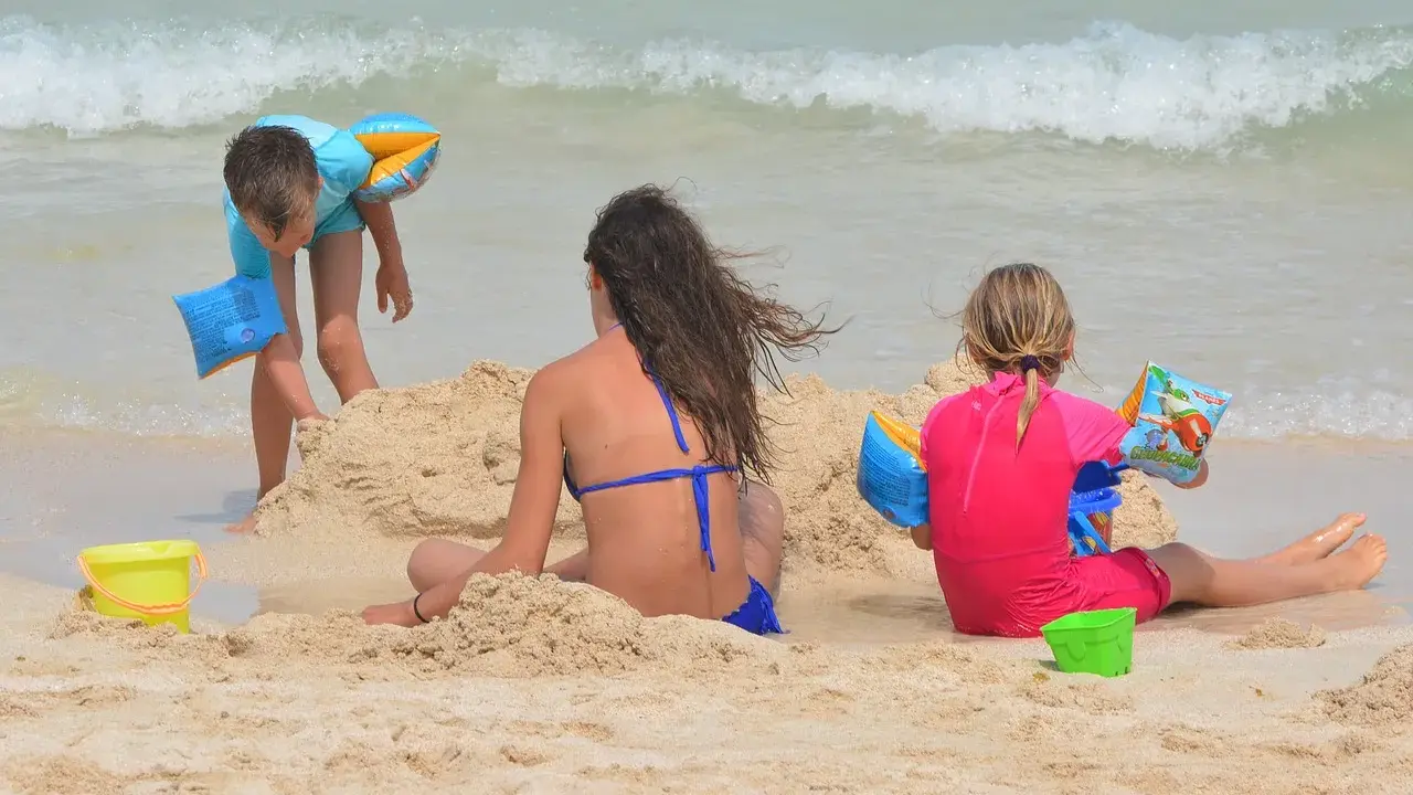 Bambini giocano sulla spiaggia, costruendo castelli di sabbia e godendosi il mare. Una giornata perfetta in una spiaggia per bambini.