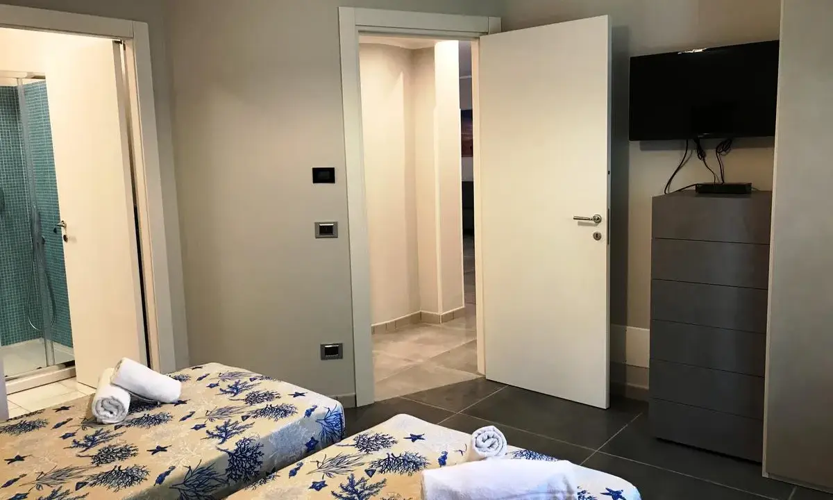Camere con letti gemelli, biancheria a tema marino, bagno con doccia e TV. Un vero eden capo vaticano.