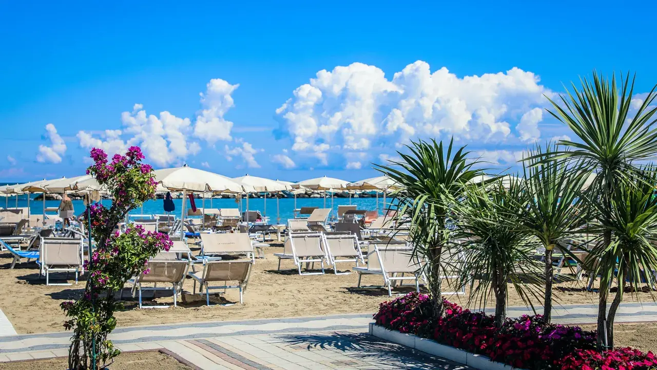 Spiaggia attrezzata con lettini e ombrelloni, palme e fiori colorati. Un'oasi di relax al Valentini Family Village, dove l'Hotel Rosalba vi aspetta.