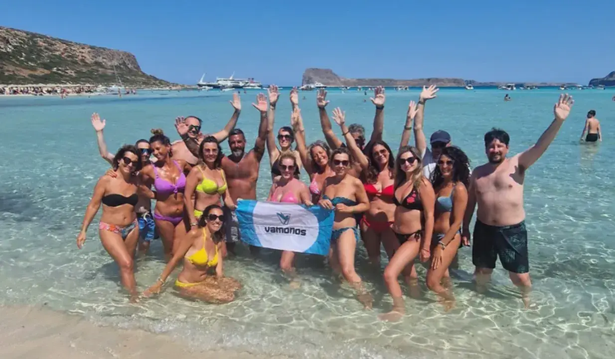 Un gruppo di amici festeggia in mare, con le braccia alzate, in una giornata di sole. Sembra proprio che festa è Ferragosto!