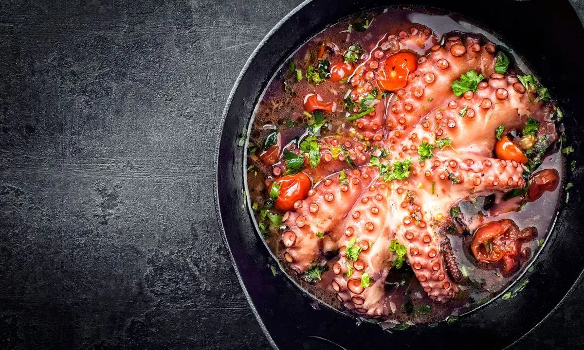 Polpo alla luciana in padella, con pomodorini e prezzemolo. Un piatto succulento e profumato, pronto per essere gustato.