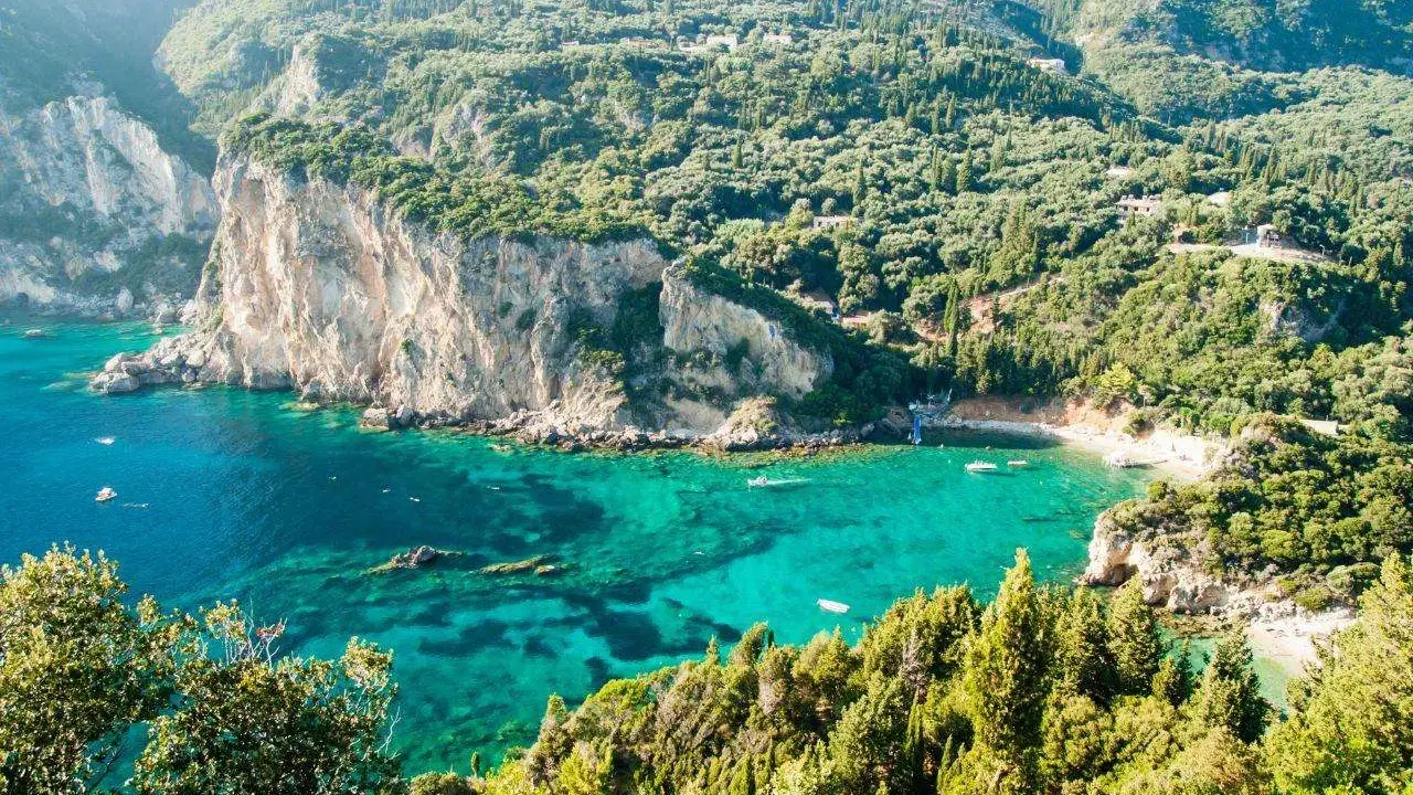 Baia verde smeraldo a Corfu, perfetta per una vacanza con bambini. Scogliere imponenti e acque cristalline invitano al gioco e all'esplorazione.