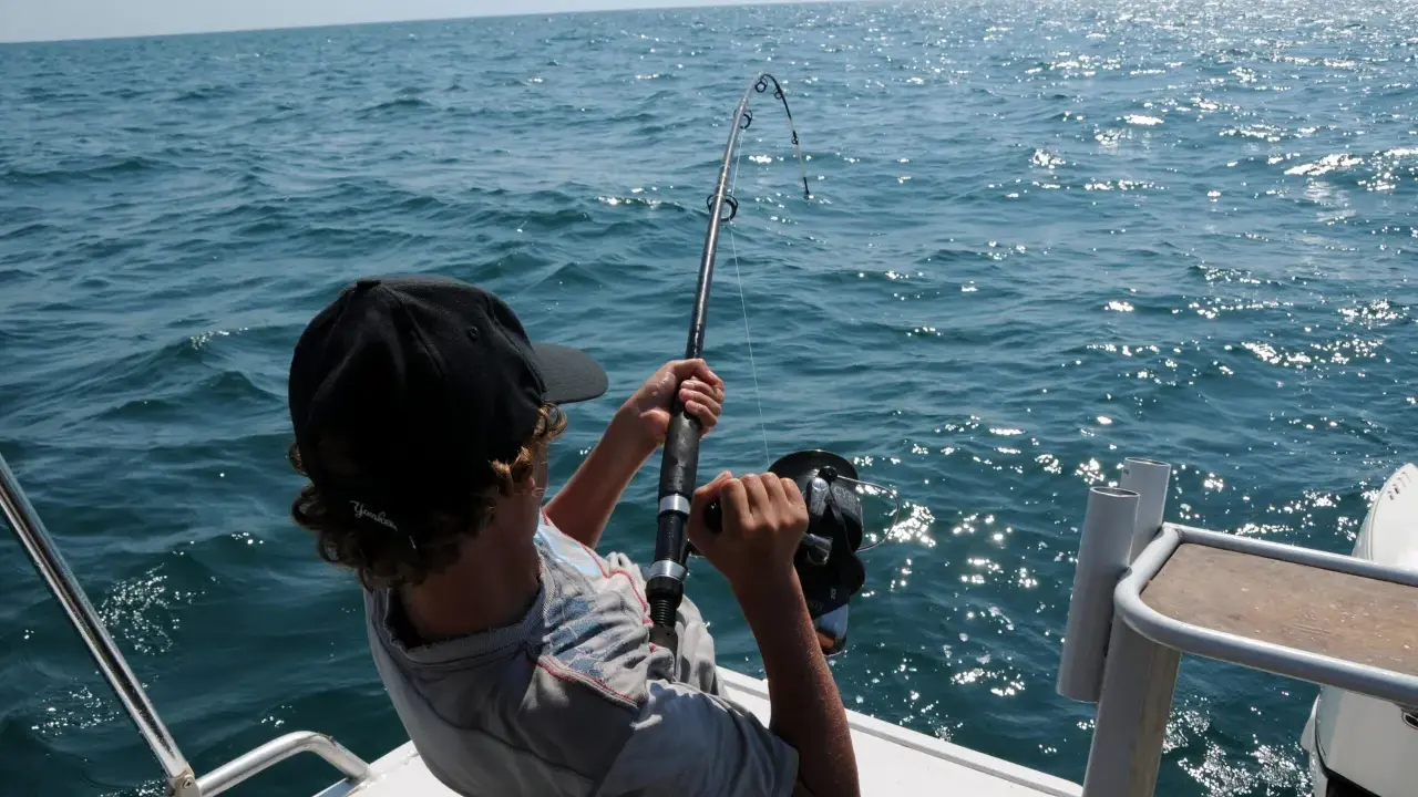 Ragazzo con cappellino nero pesca in mare, mostrando alcuni metodi di pesca con la canna.