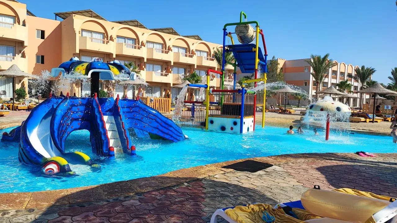 Divertimento acquatico a Marsa Alam con bambini: scivoli blu, giochi d'acqua e piscine cristalline in un resort soleggiato.