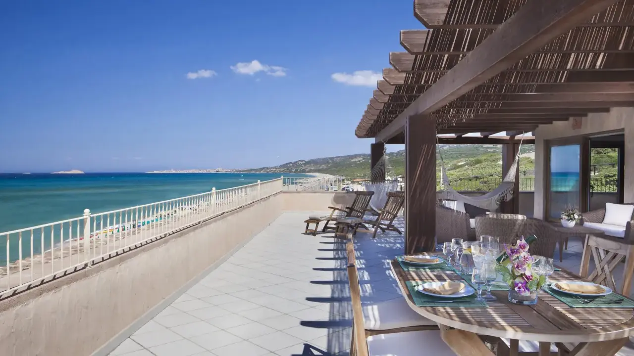 Terrazza con vista mare e tavolo apparecchiato, lettini e amaca. Un sogno al le dune resort.