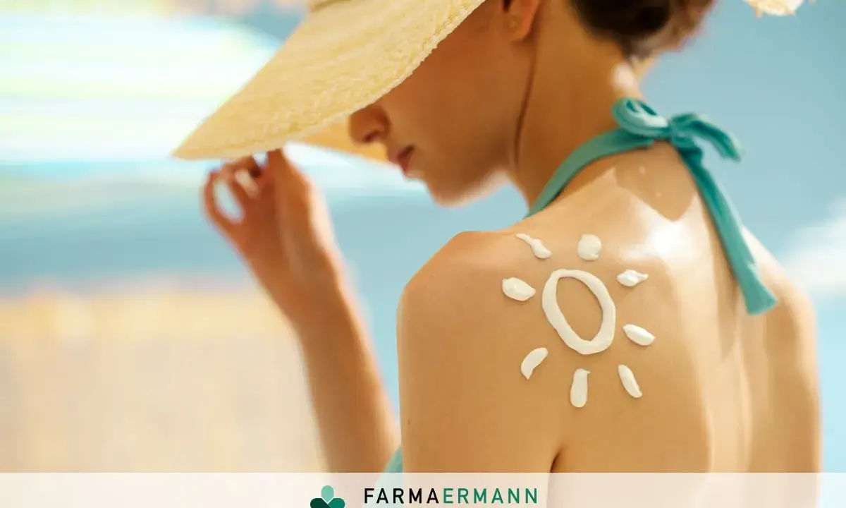 Donna con cappello di paglia e crema solare a forma di sole sulla spalla, per proteggere la pelle dal sole.