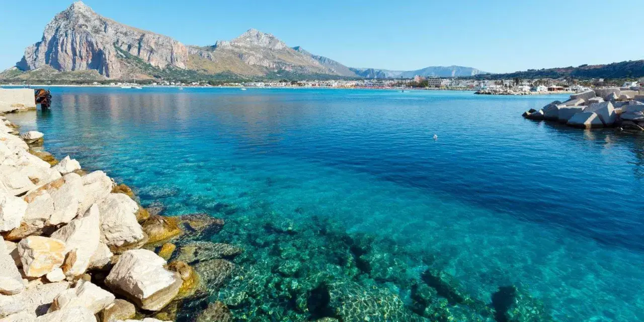 Acque cristalline a San Vito Lo Capo, perfette per una vacanza con bambini. Montagne sullo sfondo, un sogno.