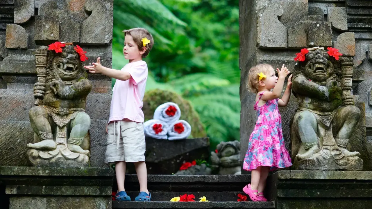 Bambini a Bali esplorano antiche statue decorate con fiori. Un'avventura indimenticabile per i più piccoli.