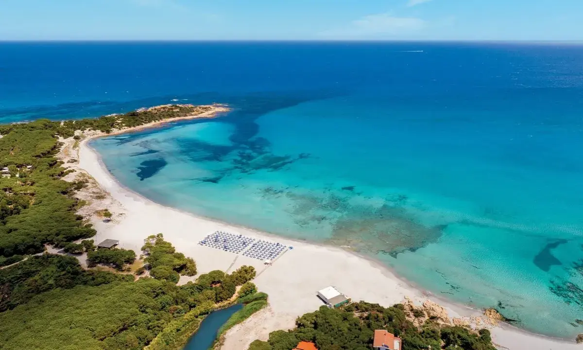 Spiaggia bianca e mare cristallino in Sardegna, ideale per villaggi per famiglie.