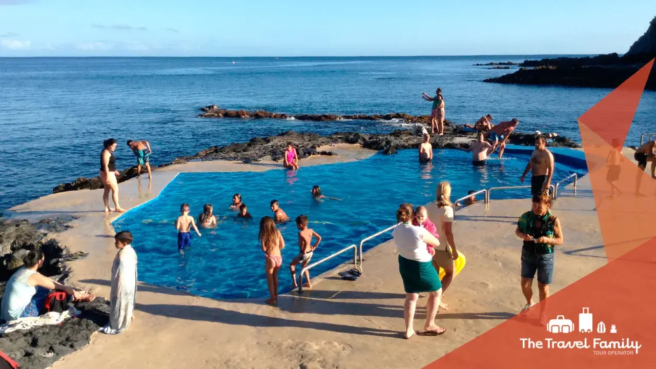 Famiglia felice alle Azzorre con bambini che nuotano in una piscina naturale.