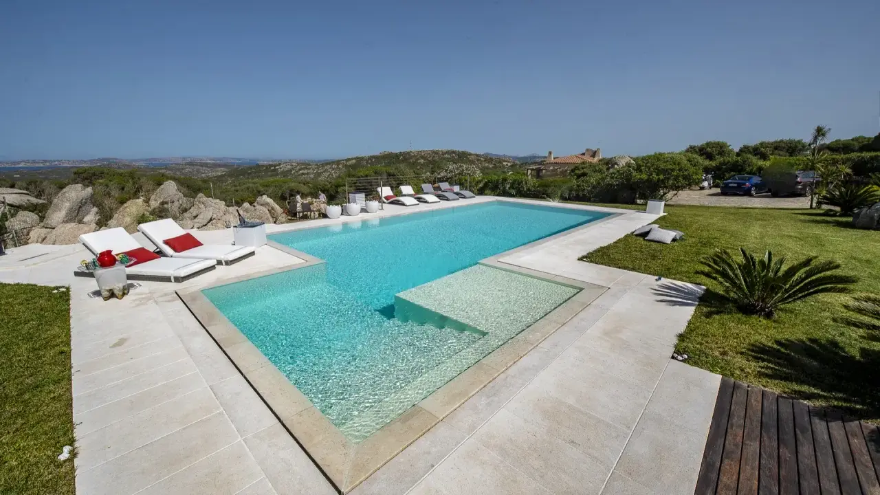 Lussuosa piscina in Sardegna, con vista mare e colline. Ideale per rilassarsi dopo un viaggio in traghetto.