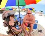 Un papà e il suo bambino si godono una giornata di sole alle Maldive con bambini, tra giochi sulla sabbia e relax sotto gli ombrelloni colorati.