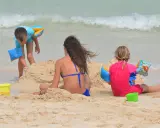 Bambini giocano sulla spiaggia, costruendo castelli di sabbia e godendosi il mare. Una giornata perfetta in una spiaggia per bambini.