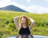 Ragazza con cappello di paglia al sole, godendosi la natura. Un modo per pensare a come abbronzarsi velocemente il viso in estate.