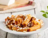 Un piatto invitante di pasta alla norma con melanzane fritte, pomodoro e ricotta salata grattugiata, pronto per essere gustato.
