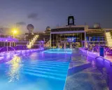 Piscine illuminate con luci viola e blu sulla MSC World Europa, con sdraio e scale illuminate.