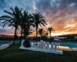 Tramonto infuocato sul Valtur Calabria Otium Resort. Palme e piscina creano un'atmosfera da sogno.