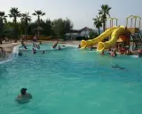 Piscina con scivoli gialli e persone che nuotano, ideale per campeggi puglia sul mare per bambini.