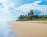 Passeggiata sulla spiaggia di Pineto mare, con un castello in lontananza tra i pini.