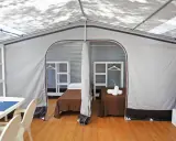 Interno di un alloggio al Family Club Marina di Ugento: due letti singoli con coperte marroni, mensole bianche e un tavolo con sedie.