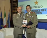 Due ufficiali in uniforme presentano un libro. Uno dei due, con un sorriso, tiene in mano il volume intitolato "Nome in codice: Ares", un'opera che narra storie di coraggio, forse ispirate a un vero pesce monaco.