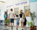 Famiglia in coda all'ufficio biglietti per la Corsica con bambini, pronti per l'avventura.