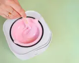 Mano con anelli mescola cera rosa in un scaldacera. Preparazione per la ceretta prima del mare.