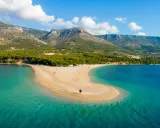 Spiaggia a forma di lingua di sabbia dorata, bagnata da acque cristalline, con montagne verdi sullo sfondo. Un angolo di paradiso in **Croazia mare**.