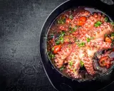 Polpo alla luciana in padella, con pomodorini e prezzemolo. Un piatto succulento e profumato, pronto per essere gustato.