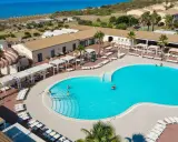 Vacanze al Sikania Eco Resort: piscina azzurra, lettini, palme e il mare all'orizzonte.