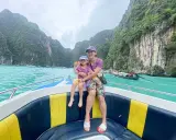 Mom and daughter in Thailand con bambini, navigano su un motoscafo tra scogliere verdi e acque turchesi.