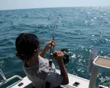 Ragazzo con cappellino nero pesca in mare, mostrando alcuni metodi di pesca con la canna.