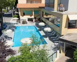 Piscina invitante e lettini prendisole al **hotel Simon Gatteo Mare**. Ombrelloni bianchi e vegetazione rigogliosa creano un'oasi di relax.