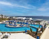 Vista panoramica del Futura Club Albatros Palace Sharm: piscine azzurre, lettini, ombrelloni blu e il mare scintillante all'orizzonte.