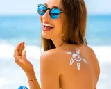 Donna sorridente in spiaggia con crema solare a forma di sole sulla schiena. L'acqua e il sale del mare la aiutano ad abbronzarsi.