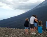 Famiglia in vacanza in Sicilia con bambini, ammira il pendio scuro di un vulcano.