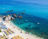 Spiaggia calabrese con ombrelloni colorati e mare cristallino, ideale tra i posti da visitare in Calabria con bambini per una vacanza indimenticabile.