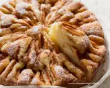 Una deliziosa torta di mele, con fette di mela disposte a raggiera e spolverata di zucchero a velo.