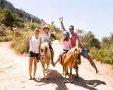 Famiglia felice a Minorca con bambini a cavallo, un'avventura indimenticabile tra sentieri soleggiati e natura rigogliosa.