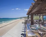 Terrazza con vista mare e tavolo apparecchiato, lettini e amaca. Un sogno al le dune resort.