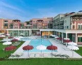 Un resort da sogno a Caorle, con piscina azzurra, lettini e ombrelloni rossi e bianchi. Un cavallino bianco potrebbe galoppare felice in questo paradiso.