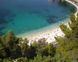 Spiaggia affollata sulla costa azzurra con bambini che giocano in acqua e prendono il sole.