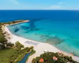 Spiaggia bianca e mare cristallino in Sardegna, ideale per villaggi per famiglie.