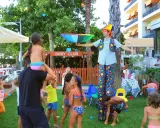 Hotel con biberoneria: animazione al Baby Club con un clown che intrattiene i bambini con palline colorate e un ombrello arcobaleno.