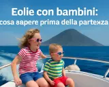 Bambini felici in barca alle Isole Eolie, con un vulcano sullo sfondo. Perfetto per una vacanza in famiglia!