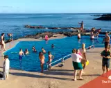 Famiglia felice alle Azzorre con bambini che nuotano in una piscina naturale.