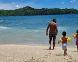Un padre cammina sulla spiaggia con i suoi due figli, pronti per un'avventura in Costa Rica con bambini.