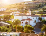 Villaggi turistici a Fuerteventura, con case bianche, palme e una chiesa con campanile, immersi nel sole dorato del tramonto.