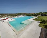 Lussuosa piscina in Sardegna, con vista mare e colline. Ideale per rilassarsi dopo un viaggio in traghetto.